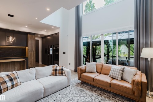 Living area featuring a two-story ceiling, tall windows with drapes, and wood-finish flooring - 1313 Clement Crest, Edmonton, AB 