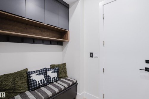 Built-in entryway bench with integrated storage, featuring a wood-finish open shelf and black overhead cabinetry - 1313 Clement Crest, Edmonton, AB 