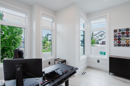 Light-filled room featuring multiple large windows with roller shades, light wood-finish flooring, white walls, and white trim - 1313 Clement Crest, Edmonton, AB 
