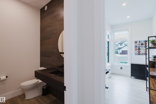 Modern powder room featuring a floating vanity with an integrated sink and black hardware - 1313 Clement Crest, Edmonton, AB 