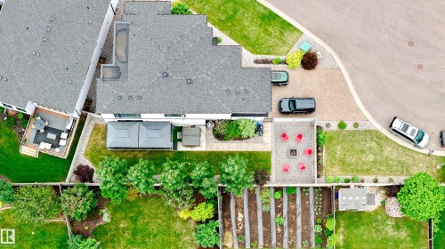 Expansive overhead property perspective featuring a large main residence with an attached deck area, a private pool on the roof, a patterned paver patio with a fire pit, and a dedicated garden plot - 1313 Clement Crest, Edmonton, AB 