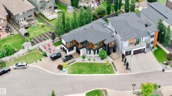Modern architectural design featuring prominent gables, dark shingled roofs, and a mix of light and dark exterior finishes - 