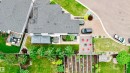 Expansive overhead property perspective featuring a large main residence with an attached deck area, a private pool on the roof, a patterned paver patio with a fire pit, and a dedicated garden plot - 1313 Clement Crest, Edmonton, AB 