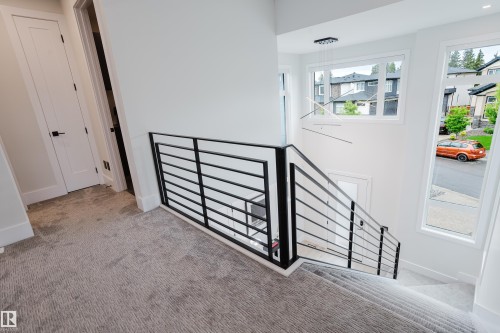 Contemporary staircase featuring a sleek black metal railing and plush grey carpeting - 1313 Clement Crest, Edmonton, AB 