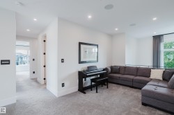 Carpeted upper-level landing featuring recessed lighting, a large window with privacy sheers, built-in ceiling speakers, and modern wall controls - 
