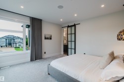 Bedroom featuring recessed lighting, light-toned carpeting, and a large window with privacy drapery - 