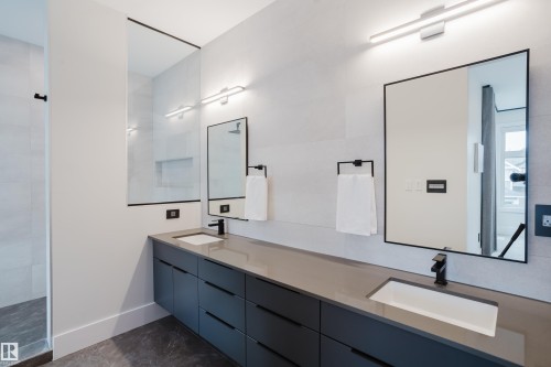 Dual floating vanities with integrated rectangular sinks, accented by matte black fixtures and under-mirror lighting - 1313 Clement Crest, Edmonton, AB 