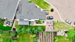 Expansive overhead property perspective featuring a large main residence with an attached deck area, a private pool on the roof, a patterned paver patio with a fire pit, and a dedicated garden plot - 