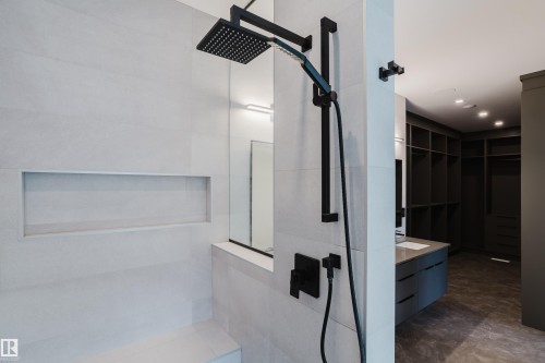 Tiled shower with a recessed niche, built-in bench, and black matte rainfall showerhead with a handheld sprayer - 1313 Clement Crest, Edmonton, AB 