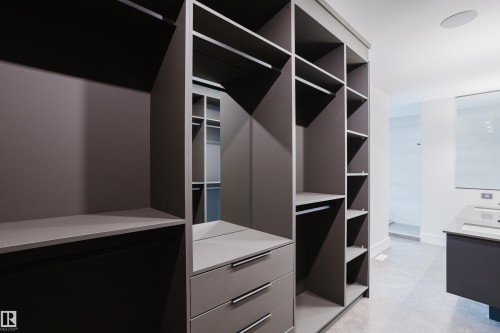 Custom built-in closet system featuring multiple shelves, hanging rods, and drawers with polished chrome hardware - 1313 Clement Crest, Edmonton, AB 
