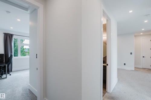 Bright interior hallway featuring recessed lighting and white doors with matte black hardware - 1313 Clement Crest, Edmonton, AB 