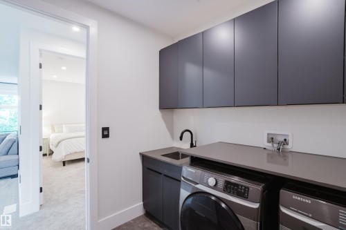 Dedicated laundry area featuring dark gray cabinetry, a built-in sink with a matte black faucet, and a light-toned countertop - 1313 Clement Crest, Edmonton, AB 