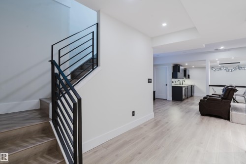 Modern staircase featuring black metal railings and light wood-finish treads - 1313 Clement Crest, Edmonton, AB 