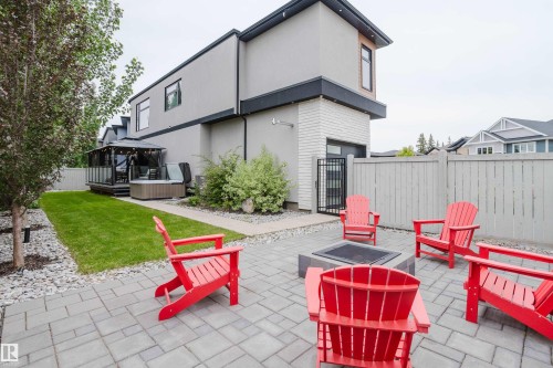 Expansive backyard featuring a paver patio with a built-in fire pit, a manicured lawn, and mature landscaping - 1313 Clement Crest, Edmonton, AB 