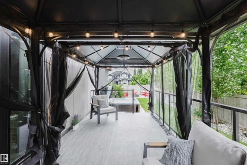 Covered outdoor patio area featuring a slatted roof structure, string lighting, and wood-finish flooring - 1313 Clement Crest, Edmonton, AB 
