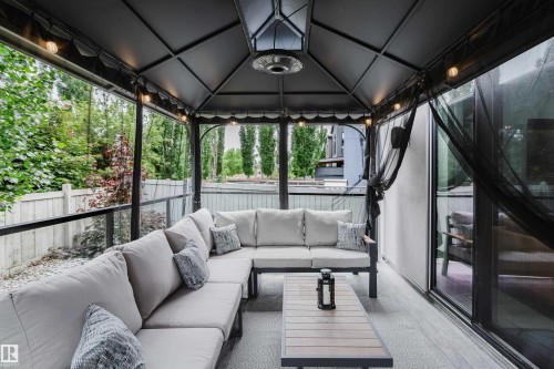 Covered patio featuring a gazebo structure, glass panel railing, wood-finish flooring, and a built-in overhead heater - 1313 Clement Crest, Edmonton, AB 