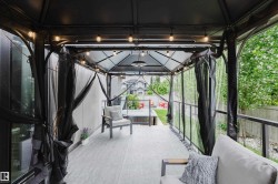 Covered outdoor patio area featuring a slatted roof structure, string lighting, and wood-finish flooring - 