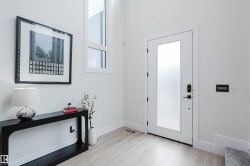 Modern entryway with wood-finish flooring and crisp white walls - 