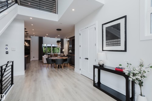 Open-concept living area featuring light wood-finish flooring, recessed lighting, a modern horizontal baluster staircase, and a double-height ceiling - 1313 Clement Crest, Edmonton, AB 