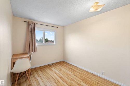 Bright interior room featuring wood-finish flooring, a single window with a curtain rod, and a ceiling-mounted light fixture - 359 Kirkpatrick Crescent, Edmonton, AB 