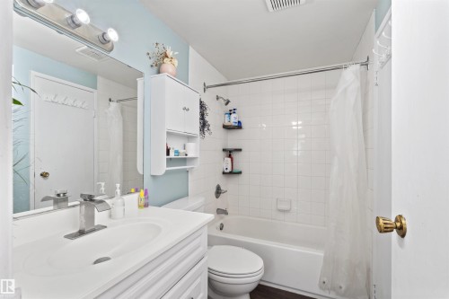 Bathroom featuring a single vanity with an integrated white sink, a chrome waterfall-style faucet, and a large wall-mounted mirror - 359 Kirkpatrick Crescent, Edmonton, AB 