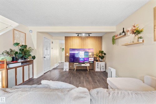 Living area featuring wood-finish flooring, a decorative slatted wood accent wall, and built-in wall shelving - 359 Kirkpatrick Crescent, Edmonton, AB 