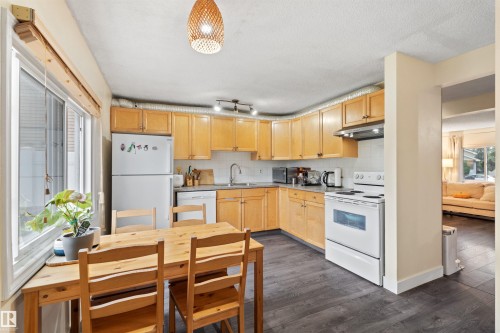 U-shaped kitchen featuring wood cabinetry, dark wood-finish flooring, a white range, a white refrigerator, and a recessed sink with a white tiled backsplash - 359 Kirkpatrick Crescent, Edmonton, AB 
