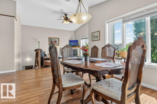 Dining area featuring wood-finish flooring, a large multi-pane window, vaulted ceilings, a ceiling fan, and a built-in light fixture - 39 Wilkinson Place, Leduc, AB 