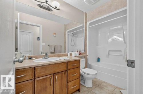 Bathroom featuring a wood-finish vanity with an integrated sink and chrome faucet - 39 Wilkinson Place, Leduc, AB 