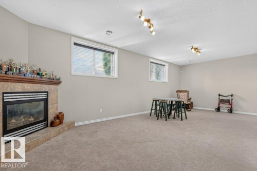 Spacious room with a gas fireplace featuring a tile surround and wood mantle - 39 Wilkinson Place, Leduc, AB 