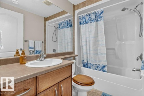 Bathroom featuring a built-in vanity with wood-finish cabinetry, an integrated white sink, and a laminate countertop - 39 Wilkinson Place, Leduc, AB 