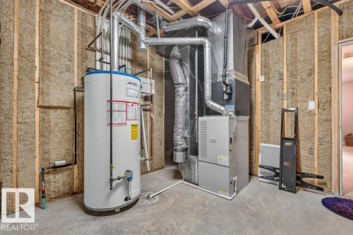 Utility room featuring a water heater, furnace, exposed wood framing, insulation, and concrete flooring - 39 Wilkinson Place, Leduc, AB 