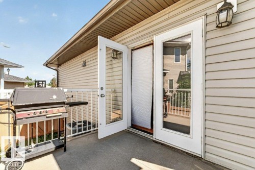 Exterior deck featuring light-colored siding, white railing, and dual glass panel doors - 39 Wilkinson Place, Leduc, AB 