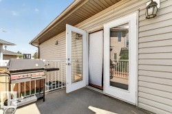 Exterior deck featuring light-colored siding, white railing, and dual glass panel doors - 