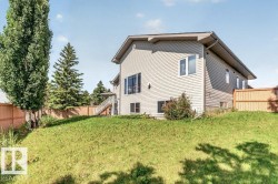 Sloped rear yard with a wooden fence and mature trees - 