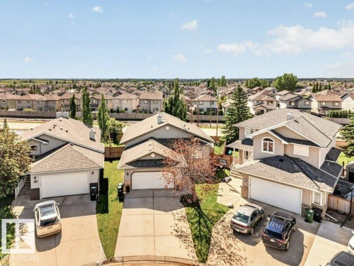 Aerial perspective of a residential neighborhood featuring multiple single-family homes with asphalt shingle roofs and integrated garages - 39 Wilkinson Place, Leduc, AB 