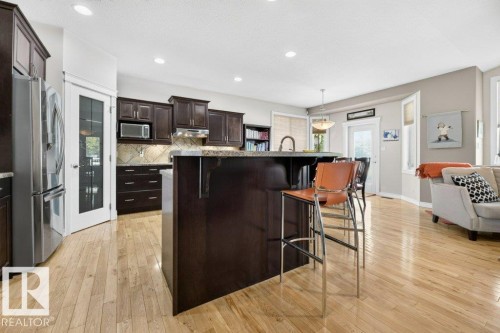 Spacious kitchen featuring dark wood cabinetry, stainless steel appliances, and a central island with an integrated sink - 5528 43 Street, Lamont, AB 