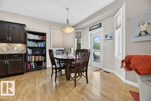 Hardwood flooring throughout a dining area featuring a bay window with natural light, a built-in bookshelf, and direct access to an outdoor area - 5528 43 Street, Lamont, AB 