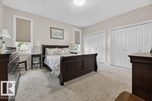 Bright room featuring two windows with privacy blinds, light-toned carpeting, and two sets of bi-fold closet doors - 5528 43 Street, Lamont, AB 