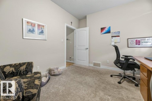 Interior room featuring light neutral wall paint, light-colored carpet flooring, a white paneled door, and a built-in wood-finish desk - 5528 43 Street, Lamont, AB 