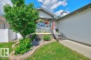Front exterior featuring a covered porch, white railing, and stone façade accents - 5528 43 Street, Lamont, AB 