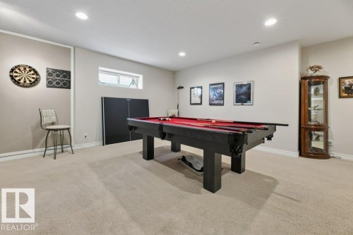 Spacious recreation room featuring neutral carpeting, recessed ceiling lighting, and a horizontal window - 5528 43 Street, Lamont, AB 