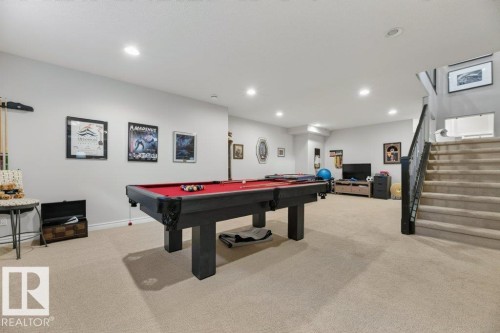Spacious recreation room featuring recessed lighting, light-toned carpeting, and a carpeted staircase with a dark-finished railing - 5528 43 Street, Lamont, AB 