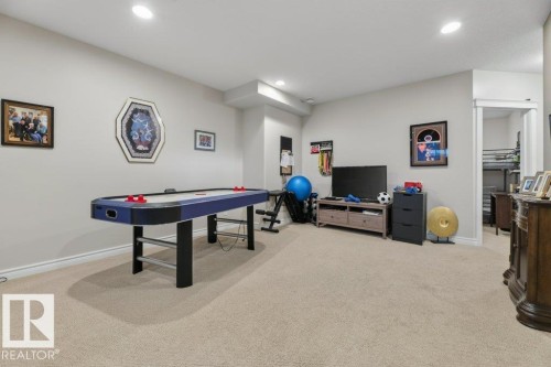 Carpeted recreation area with recessed lighting, light-toned walls, and a visible doorway leading to an additional space - 5528 43 Street, Lamont, AB 