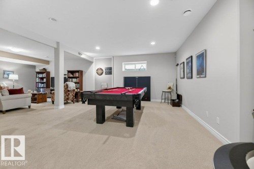 Expansive recreation room featuring light-toned carpet flooring, recessed ceiling lighting, and a window providing natural illumination - 5528 43 Street, Lamont, AB 