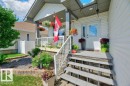 Inviting front porch featuring a white vinyl railing, stone veneer accents, and a panel door with decorative glass - 5528 43 Street, Lamont, AB 