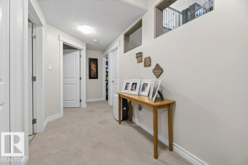 Carpeted hallway featuring light neutral wall tones, white trim, and white paneled doors - 5528 43 Street, Lamont, AB 
