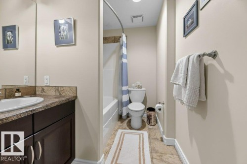 Bathroom featuring a vanity with a white oval sink, dark wood-finish cabinetry, and a stone-finish countertop - 5528 43 Street, Lamont, AB 