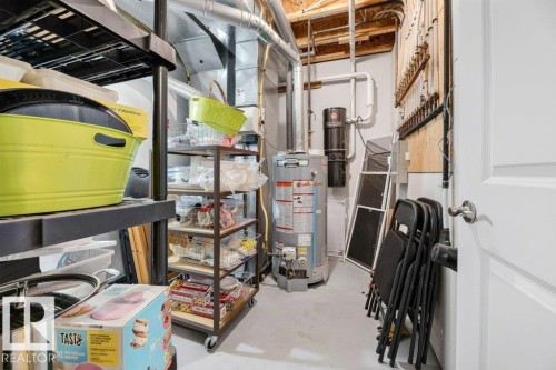 Utility space featuring a water heater, central vacuum system, and exposed ceiling joists - 5528 43 Street, Lamont, AB 