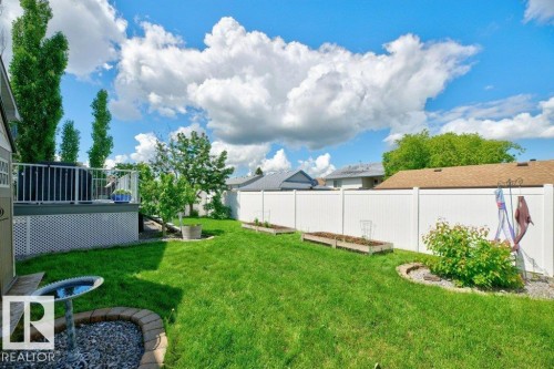Spacious backyard featuring a manicured lawn, a white privacy fence, and a raised wooden deck with white railings - 5528 43 Street, Lamont, AB 